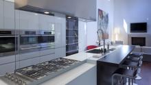 View of kitchen showing the equipped back section, breakfast bar and boiserie with living room in background.