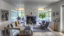 Overall view of living area with central fireplace flanked by large expanses of windows.