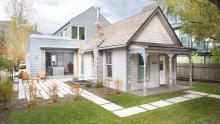 Mining Modern: Overall view of existing house in relation to addition with sliding doors in open position to reveal kitchen.